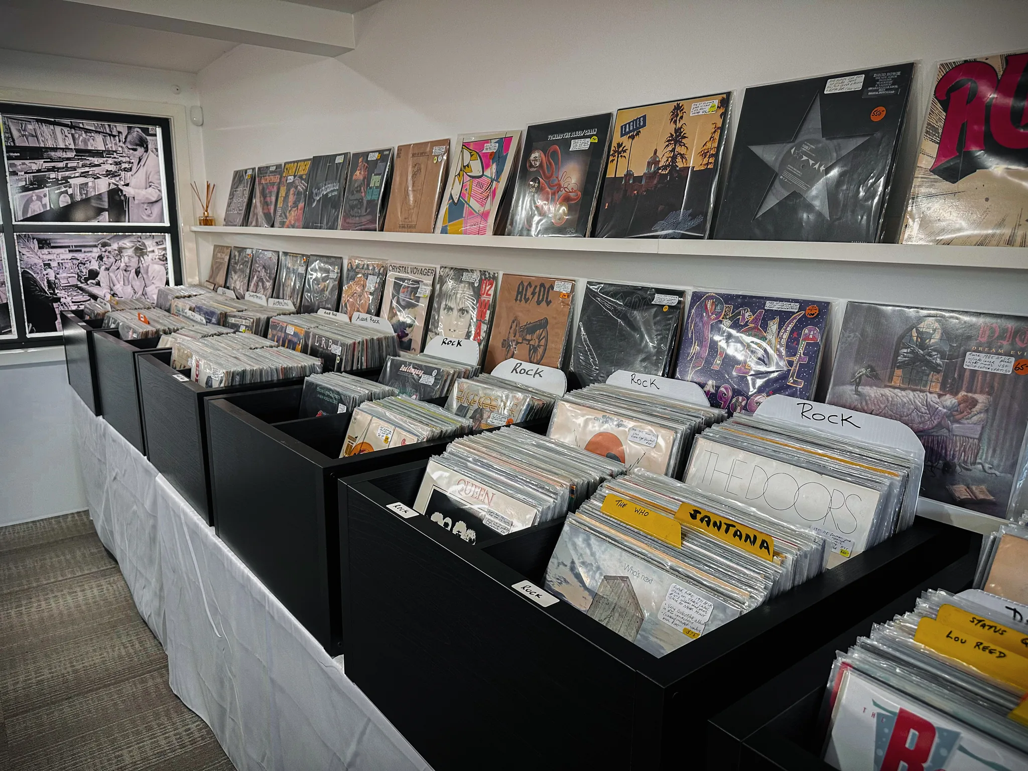 Rows of rock records filed in crates — The Doors, The Who, Queen and Santana — with classic albums on the display shelf